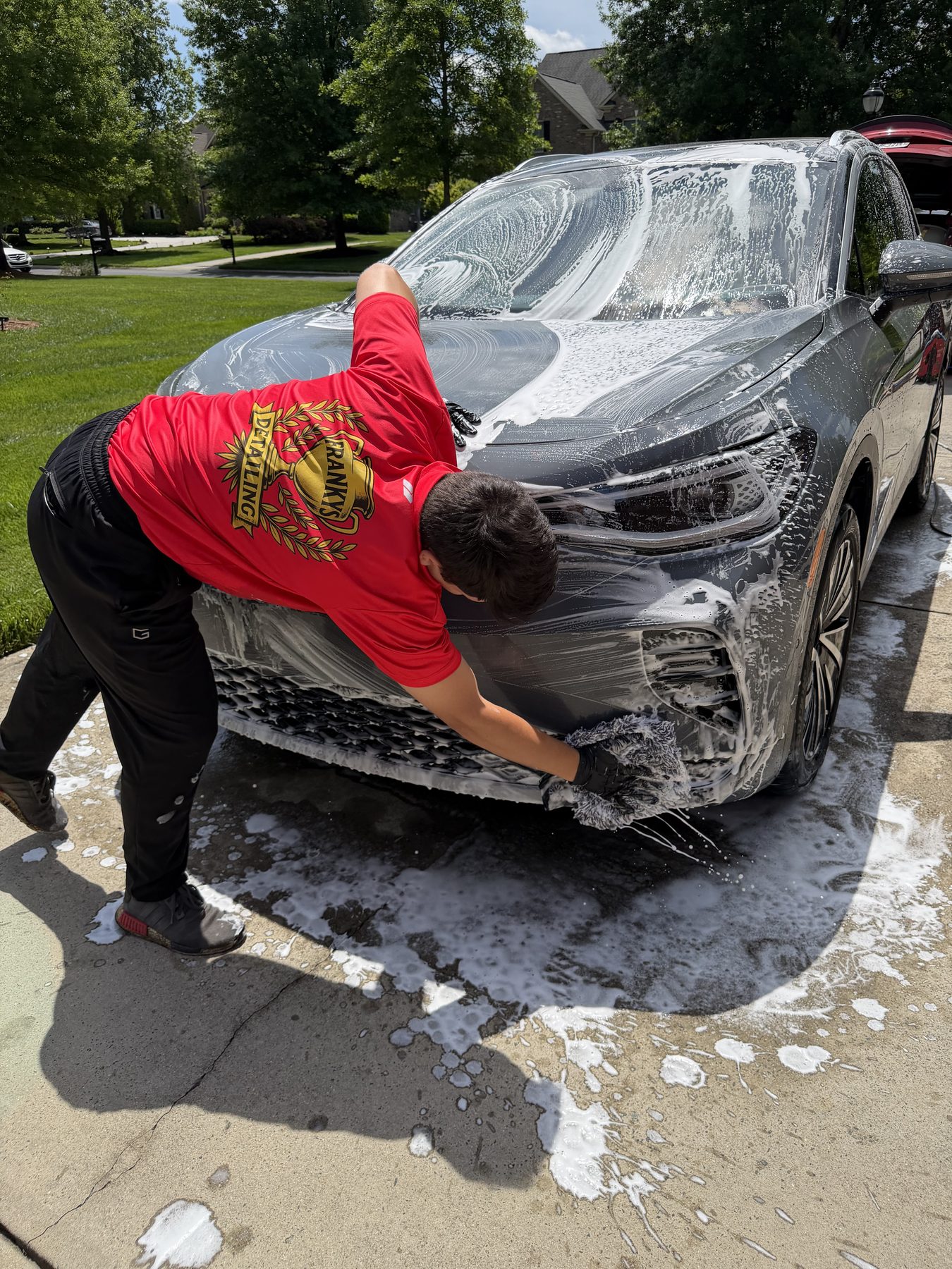 Foam wash mid-pass on the front of a dark SUV